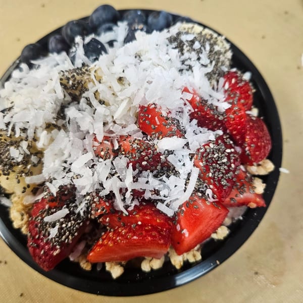 A Coco Loco smoothie bowl topped with strawberries, blueberries, shredded coconut, and chia seeds.