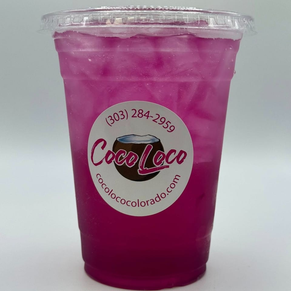 A vibrant pink Coco Loco smoothie with ice in a clear plastic cup with the brand's logo.